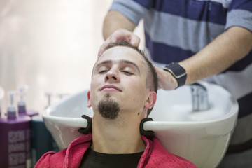 Washing male customer hair at hairdresser salon