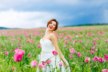 happy bride in white dress  having fun in flower poppy field 