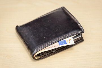 leather wallet with 50 Euro banknote inside on wooden table

