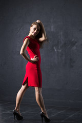 Fototapeta premium Lady in red dress posing against textured wall background