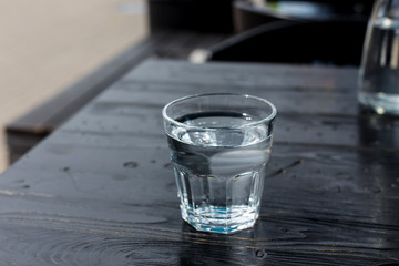 A glass of water on the wooden table of a cafe terrace