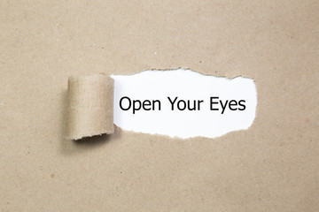 The text Open Your Eyes appearing behind torn paper. 