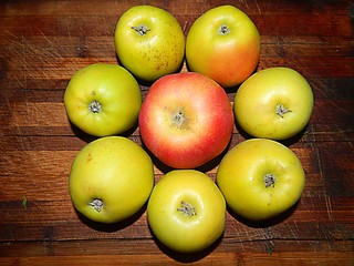 On a wooden board laid out fresh fruit. Apples yellow, red, green are like a flower