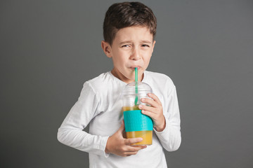 Little funny boy drinking a fresh juice through a straw