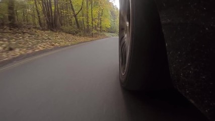 Schnelles Auto fährt auf Landstraße durch einen Wald