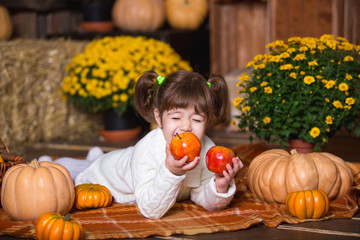 Fototapeta premium Portrait of adorable smiling girl posing with orange pumpkin in fall wooden interior.