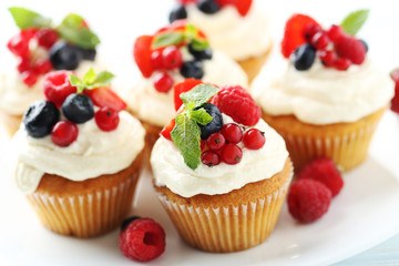 Tasty cupcakes with berries on white wooden table