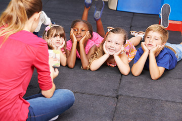 Children listening to story from book in kindergarten