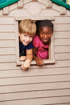 Two Children Looking Through Window In Playhouse