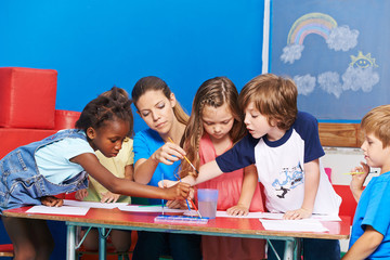 Children painting with water color in kindergarten