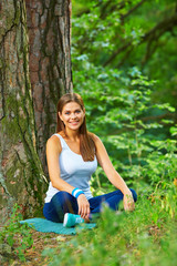 Young woman resting in forest. Green wild wood background.