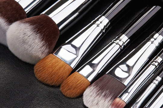 Makeup brushes set on black leather background