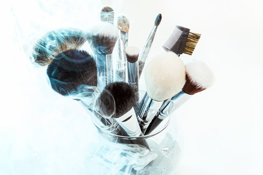 Makeup brushes in a glass vase. Blue smoke