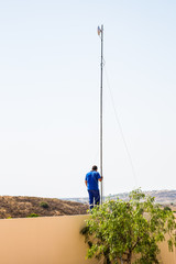 Obraz premium Installation of a radio frequency internet antenna receiver requiring a long pole and cable support on a wall of a property in Spain.