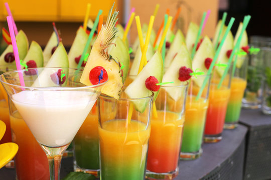 Assortment of fresh tropical cocktails with straw , fruits and flags