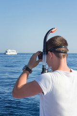 a young man against the sea with diving mask for snorkelling