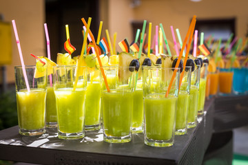 Assortment of fresh tropical cocktails with straw , fruits and flags 