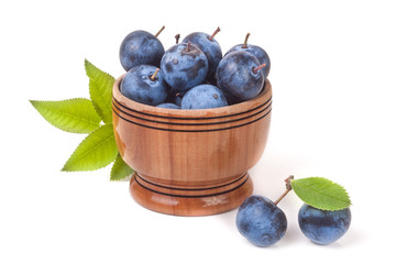 blackthorn berries with leaves in a wooden bowl isolated on white background
