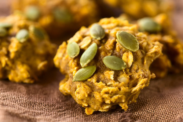 Kürbis- und Haferflockenplätzchen mit Kürbiskernen bestreut, fotografiert mit natürlichem Licht (Selektiver Fokus, Fokus in die Mitte des ersten Plätzchens)