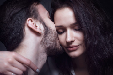 Beautiful cute loving couple in a studio with dark walls