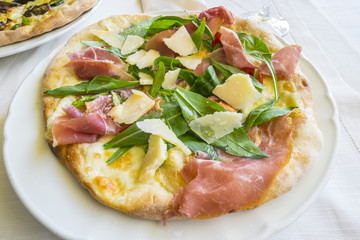 Pizza with Raw Ham and Arugula, and Shaved Parmesan Cheese 