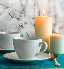 White cups and candles on the background of snow-covered garden