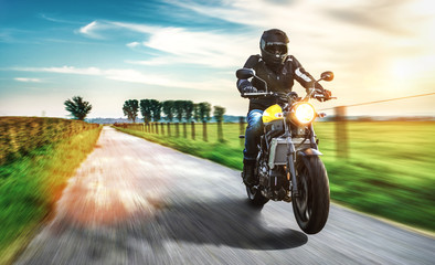 Motorrad fährt auf freier Landstrasse in den Sonnenuntergang