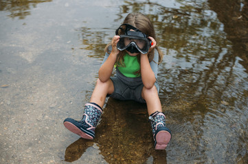 beautiful girl playing in the puddle of water with neoprene and