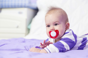 Portrait of sweet baby girl with pacifier .