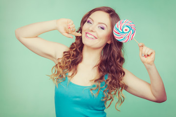 Smiling girl with lollipop candy on teal
