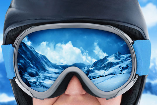 A mountain range reflected in the ski mask. Girl wearing a ski mask