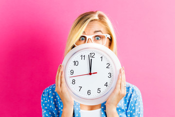 Woman holding clock showing nearly 12