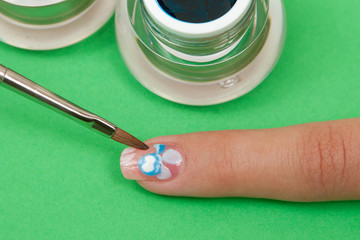 Professional manicurist makes the new gel polish manicure. Finger closeup on a green background
