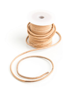 Brown leather cord on plastic spool