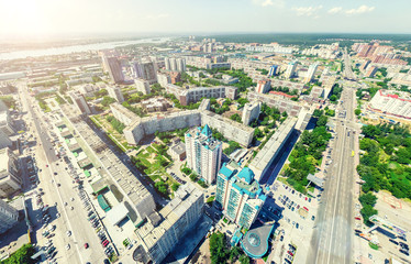 Fototapeta premium Aerial city view with crossroads and roads, houses, buildings, parks and parking lots, bridges. Urban landscape. Copter shot. Panoramic image.