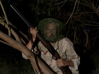 Man in mosquito net ready to hunt with hunting rifle
