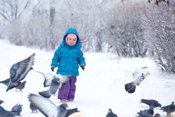 Fototapeta na wymiar Cute little girl scared pigeons