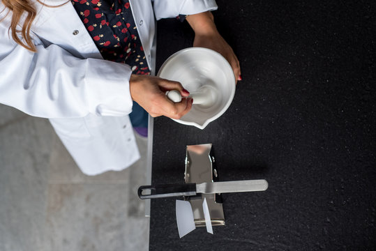 Apothekerin Pharmazeutisch-technische Assistentin im wei&szlig;en Kittel stellt Rezeptur in R&uuml;hrschale her. Blick von oben am Arbeitsplatz Apotheke.