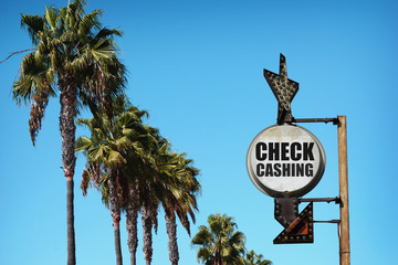 aged and worn vintage photo of check cashing sign and palm trees