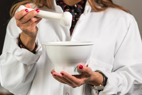 Apothekerin Pharmazeutisch-technische Assistentin stellt Rezeptur in R&uuml;hrschale her und &uuml;berpr&uuml;ft Creme am Pistill. Arbeitsplatz Apotheke