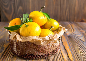 Ripe tangerines in a small metal basket