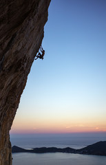 Rock climber on overhanging cliff at sunset. Kalymnos Island, Greece.