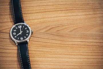 wristwatch on wooden table with blank space for text on the right side - clockwise on 8 o'clock morning