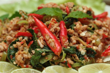 Close up of fried spicy basil with minced pork topped sliced green lemon and and lettuce is top ten of popular Thai food. Selective focus.