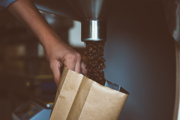 close-up of man filling package with coffee beans - 124572423