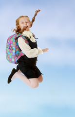Obraz premium Girl schoolgirl with a satchel behind shoulders jumps