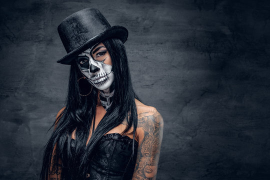A woman with skull make up in top hat on Halloween.