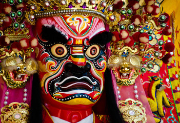 Fototapeta premium Colorful face of a Chinese deity. The face of the diety and the head ornament are refined pieces of artwork. There are red, pink, yellow, white, yellow, blue and green colors on it. 