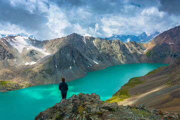 Girl standing on a large rock on a background of a mountain lake