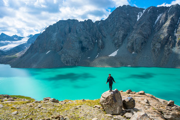 Girl standing on a large rock on a background of a mountain lake